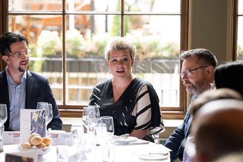 Three delegates engage in a discussion about insurance fraud at a roundtable.